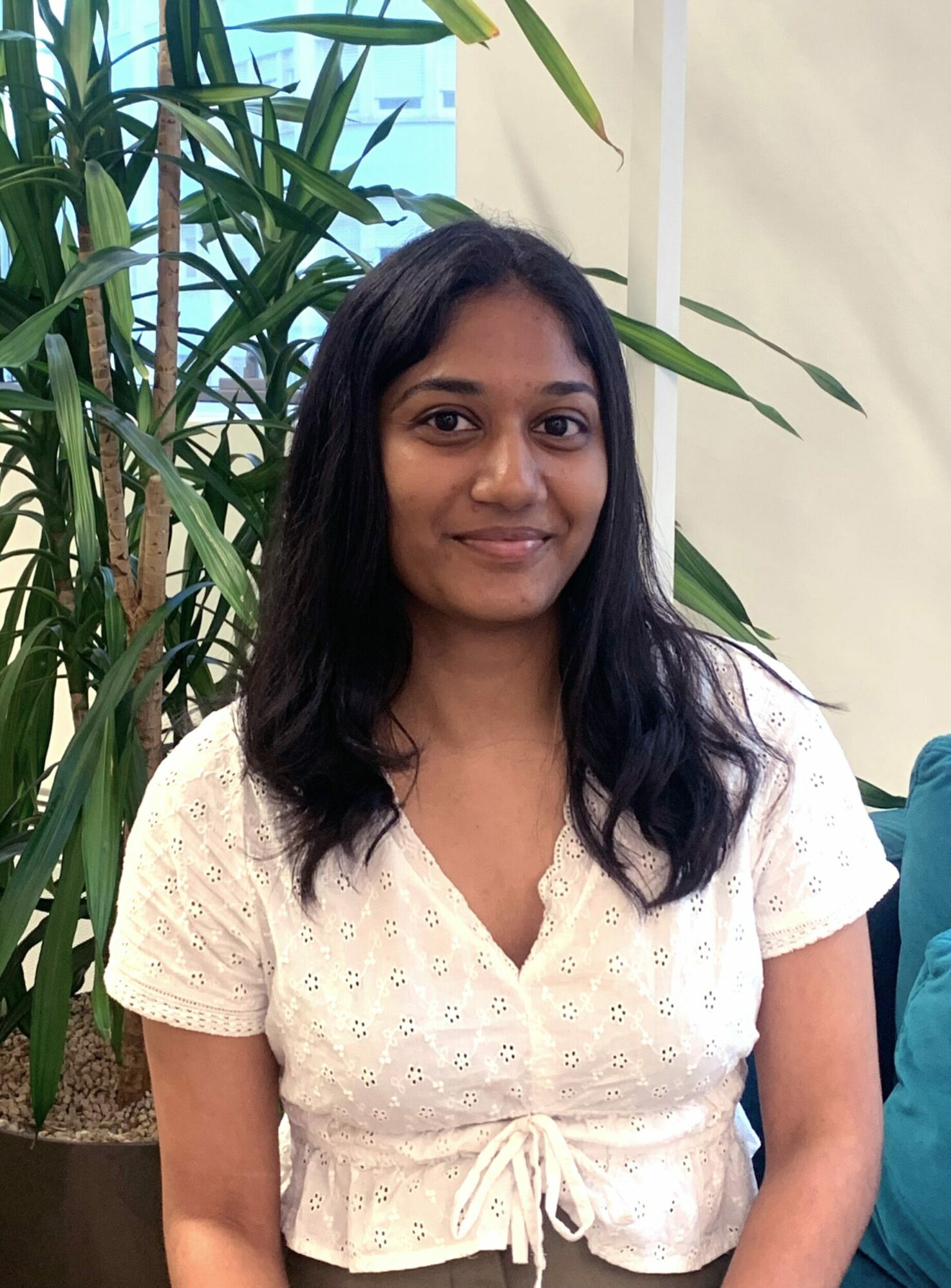 A girl sitting next to a plant posing for a portrait