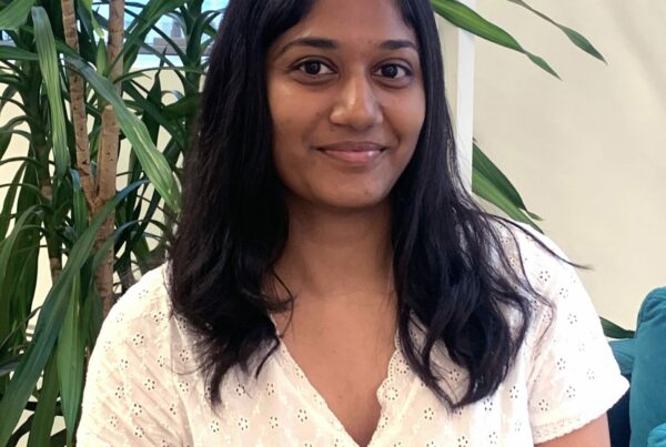 A girl sitting next to a plant posing for a portrait